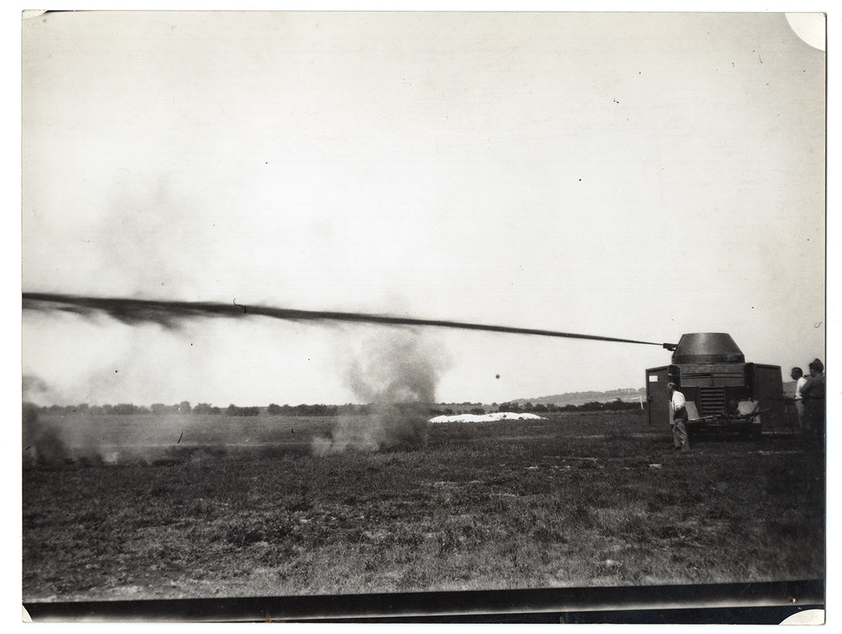 Collections Fraser Flamethrower Commer Flamethrower Black and white photograph from the early 1940s showing an armoured van-style vehicle with an experimental flamethrower on the roof - firing a jet of burning fuel.