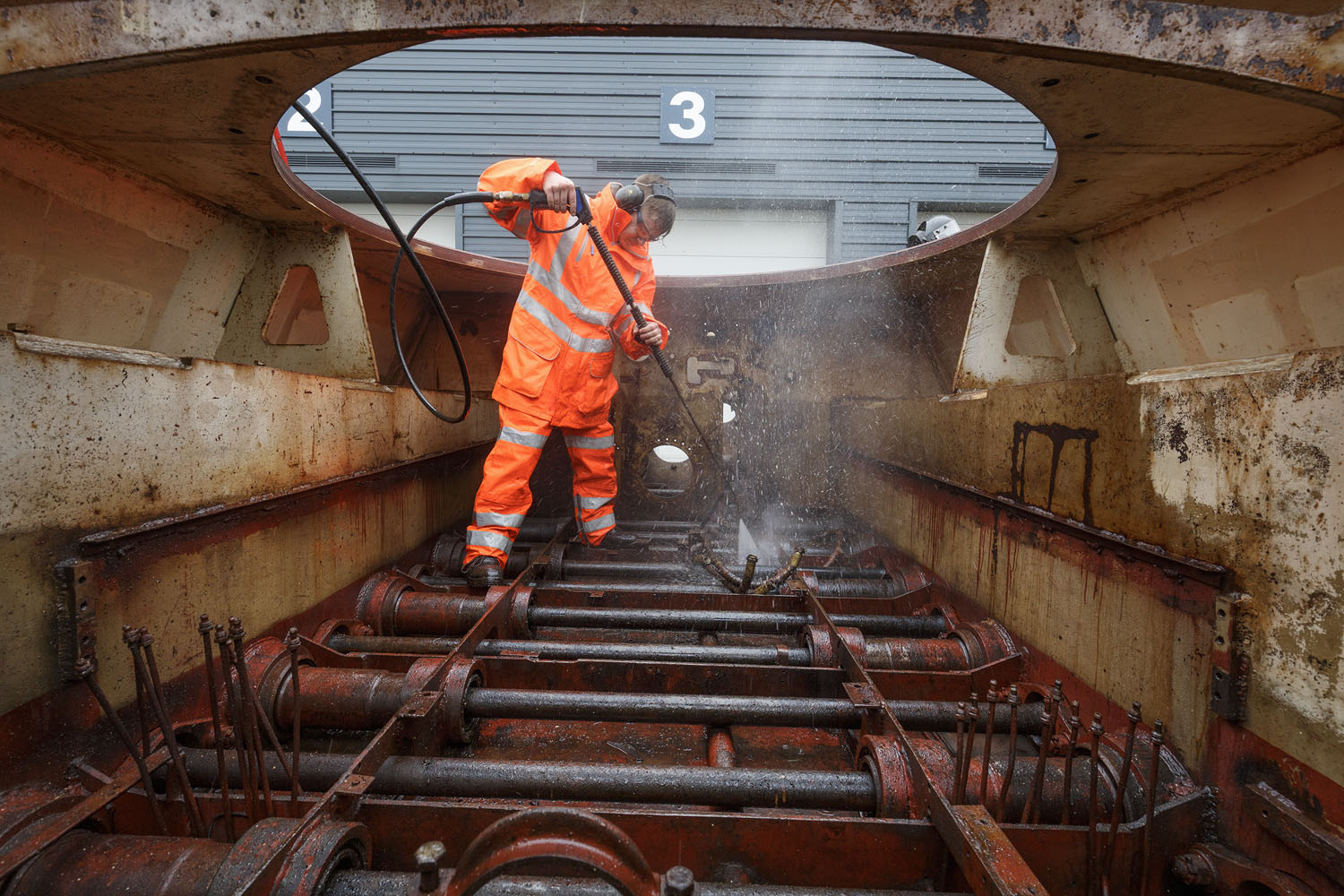 King Tiger V2 Hull Jetwash 199 workshop team member in hi-vis clothing jet washing the hull of king tiger