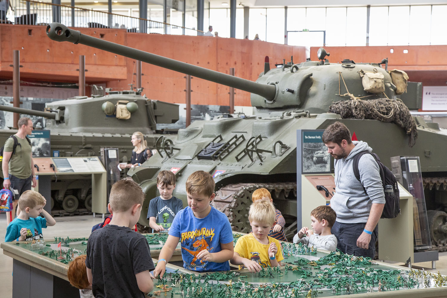 Visitors 2022_002 Children playing with toy soldiers with tanks in the background