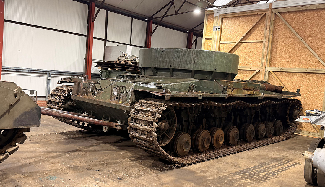 Conqueror in workshop Photograph of a green tank in a shed