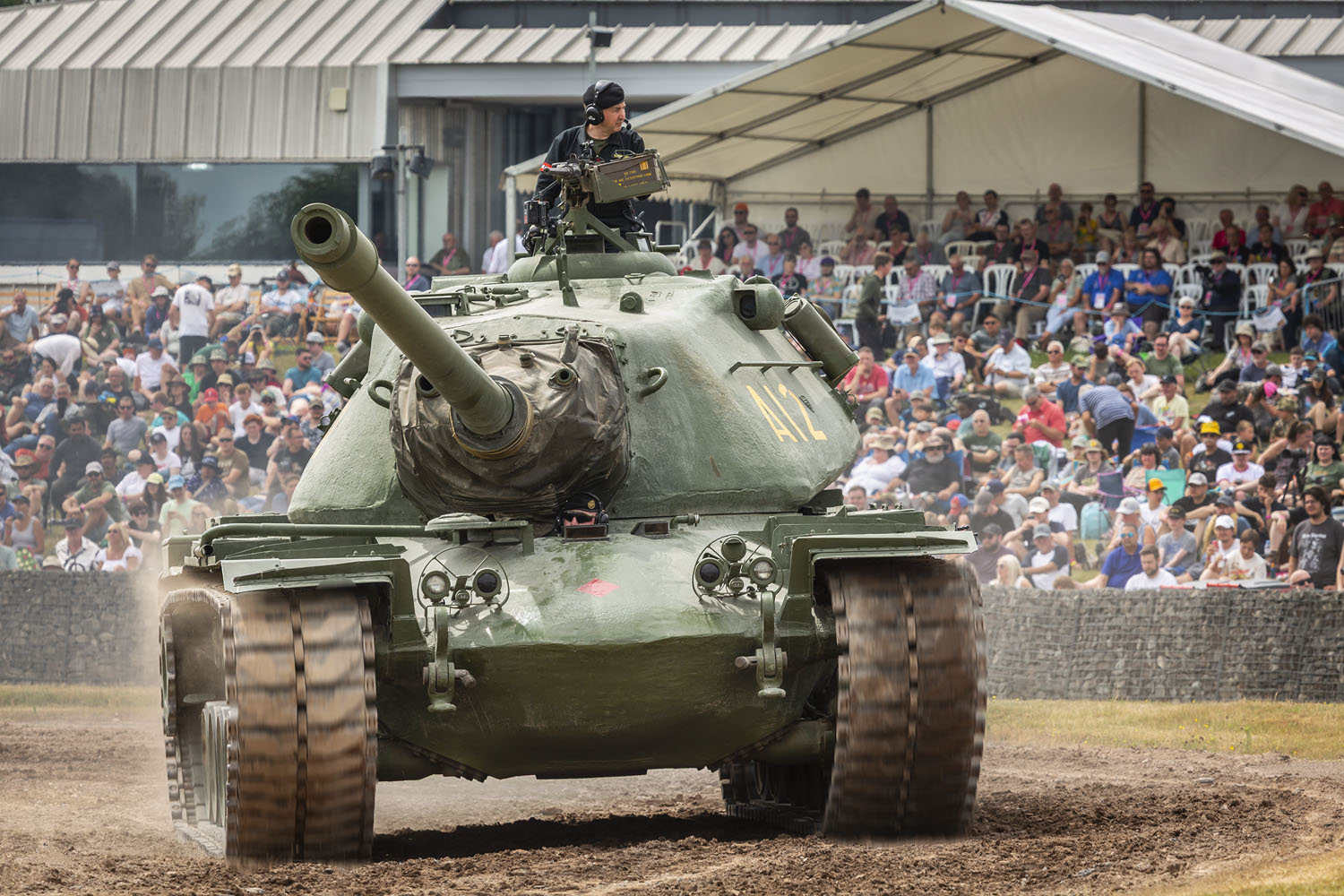 TANKFEST is the world's best display of historic moving armour, attracting fans from around the globe. Tank driving around the TANKFEST kuwait arena wioth crowds behind