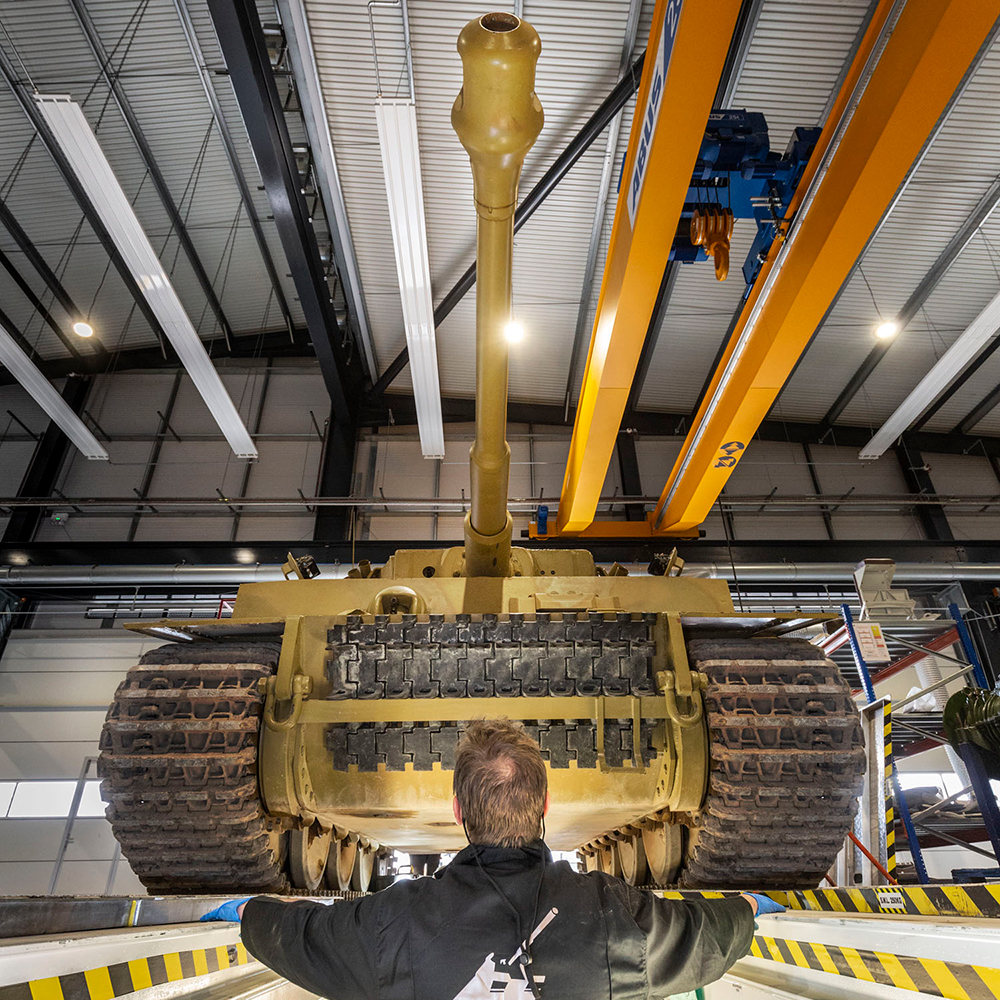 Photograph of Tiger 131 from underneath, with a man in black overalls standing underneath.