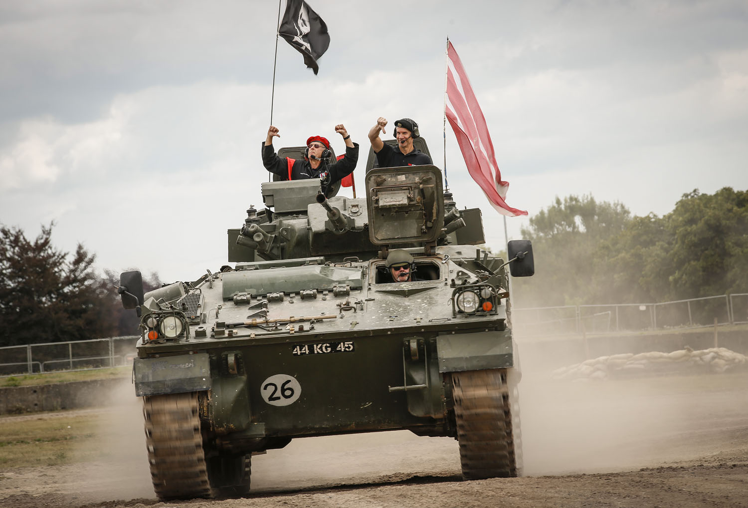 Tank battle reenactment Tank driving around the arena flying a pirate flag with 2 people inside